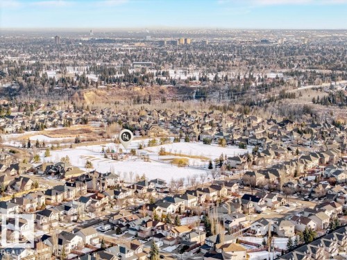Aerial view of the surrounding residential neighborhood featuring houses with diverse roof styles, an open field and a wooded area in the distance - 217 160 Magrath Road, Edmonton, AB - Outdoor With View