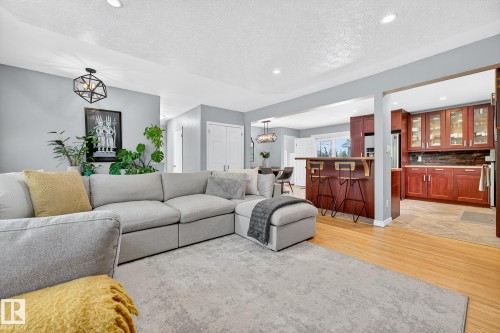 The main living area features light hardwood flooring, recessed lighting, and a contemporary light fixture - 15701 92A Avenue, Edmonton, AB - Indoor Photo Showing Living Room