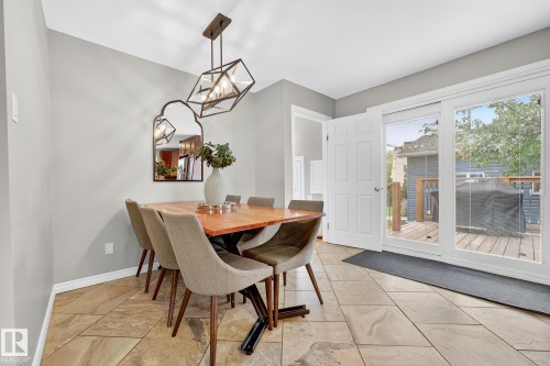 This dining area features a stylish light fixture, a wood table, and tiled flooring - 15701 92A Avenue, Edmonton, AB - Indoor Photo Showing Dining Room