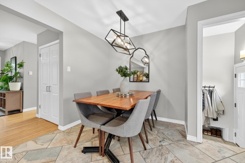 Dining area featuring light grey walls, a modern geometric chandelier, and natural stone tile flooring - 15701 92A Avenue, Edmonton, AB - Indoor Photo Showing Dining Room