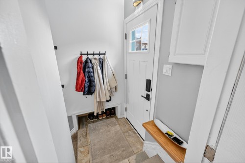 Entryway featuring a white paneled door with glass inserts, wall-mounted coat hooks, and stone tile flooring - 15701 92A Avenue, Edmonton, AB - Indoor