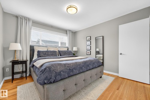 The property features hardwood floors, a large window with blinds and curtains, and a ceiling light fixture - 15701 92A Avenue, Edmonton, AB - Indoor Photo Showing Bedroom