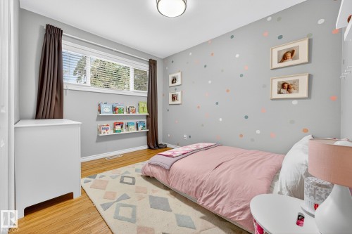 This room features hardwood floors, a large window with blinds and curtains, and a ceiling light fixture - 15701 92A Avenue, Edmonton, AB - Indoor Photo Showing Bedroom