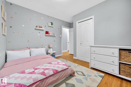 This room features hardwood flooring, a white closet door, and a white dresser with wicker baskets - 15701 92A Avenue, Edmonton, AB - Indoor Photo Showing Bedroom