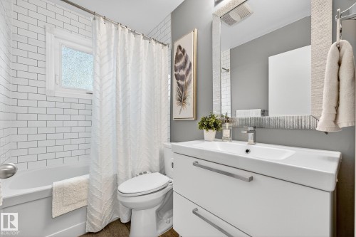 Bathroom featuring a white subway tile shower surround with a window, a white vanity with an integrated sink, and a framed mirror - 15701 92A Avenue, Edmonton, AB - Indoor Photo Showing Bathroom