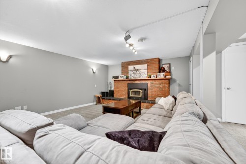 The living room features a brick fireplace with an insert, sconce lighting, and track lighting - 15701 92A Avenue, Edmonton, AB - Indoor Photo Showing Living Room With Fireplace