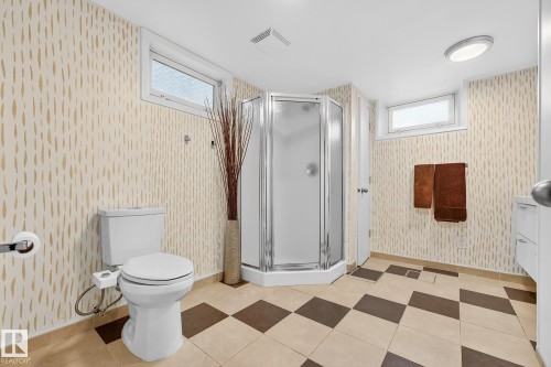 This bathroom features a corner shower enclosure, a toilet, and patterned tile flooring - 15701 92A Avenue, Edmonton, AB - Indoor Photo Showing Bathroom