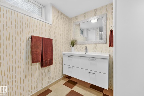 Bathroom featuring patterned wallpaper, a white floating vanity with a vessel sink, and a framed mirror - 15701 92A Avenue, Edmonton, AB - Indoor Photo Showing Bathroom