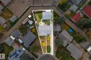 Aerial view of the property, featuring two buildings with grey roofs, a paved driveway, and a backyard with a circular patio area - 15701 92A Avenue, Edmonton, AB  - Outdoor With View 