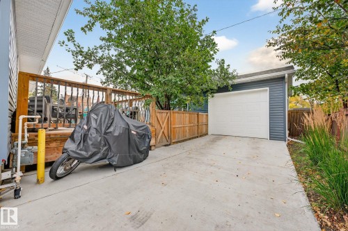 The property features a spacious detached garage with a white garage door, a concrete driveway, and a wooden deck with a railing - 15701 92A Avenue, Edmonton, AB - Outdoor With Exterior