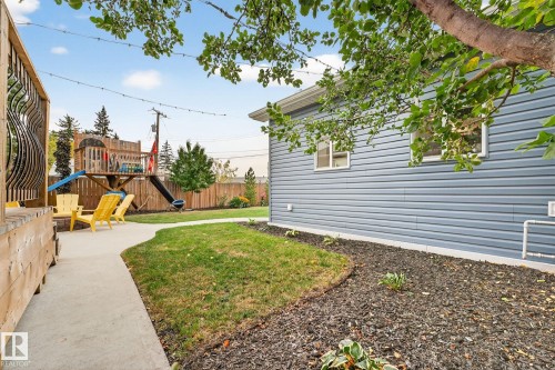 The property includes a spacious yard with a lawn, a paved walkway, and a landscaped area with dark mulch - 15701 92A Avenue, Edmonton, AB - Outdoor