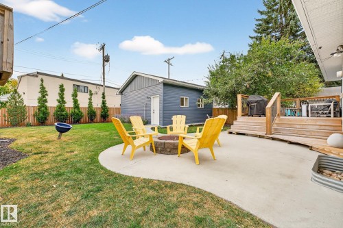 The property features a spacious backyard with a well-maintained lawn, a concrete patio, and a fire pit - 15701 92A Avenue, Edmonton, AB - Outdoor With Deck Patio Veranda