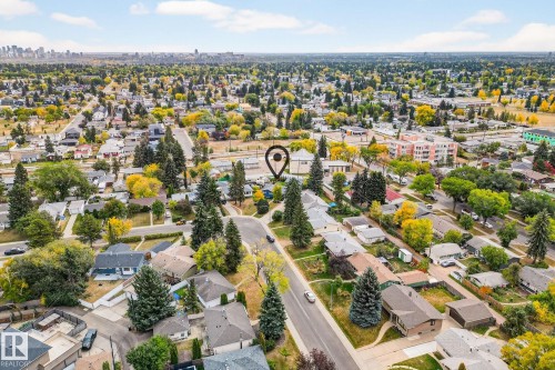 Aerial view of the neighborhood, showcasing residential properties with mature trees and a distant cityscape under a bright sky - 15701 92A Avenue, Edmonton, AB - Outdoor With View