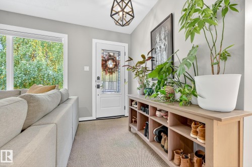 Entryway featuring a white door with decorative glass inserts, a large window providing views of greenery, and a contemporary ceiling light fixture - 15701 92A Avenue, Edmonton, AB - Indoor Photo Showing Other Room