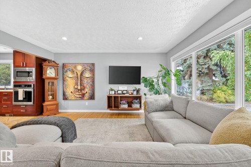 The living area features hardwood flooring, large windows, and a generous sectional sofa - 15701 92A Avenue, Edmonton, AB - Indoor Photo Showing Living Room