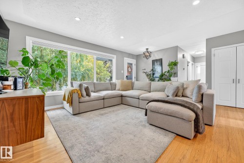 The living area features hardwood floors, a large window providing views of greenery, and recessed lighting - 15701 92A Avenue, Edmonton, AB - Indoor Photo Showing Living Room