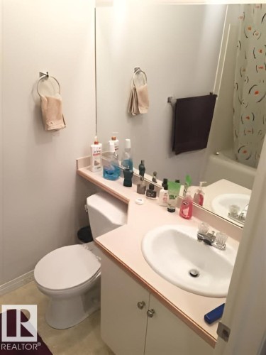 Bathroom featuring a vanity with a white basin sink, a toilet, and a shower with a patterned curtain - 136 16221 95 Street, Edmonton, AB - Indoor Photo Showing Bathroom