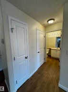 Hallway featuring wood-finish flooring, white paneled doors, and a ceiling-mounted light fixture - 