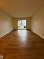 Spacious room featuring wood-finish flooring, white baseboards, and neutral wall tones - 