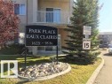 A clear view of the property's main sign, featuring "PARK PLACE EAUX CLAIRES" and the address 16221 – 95 St., surrounded by a well-maintained lawn and decorative rocks - 136 16221 95 Street, Edmonton, AB  - Outdoor With Balcony 