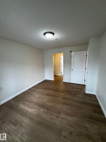 Spacious room featuring wood-finish flooring, white baseboards, and a neutral wall palette - 136 16221 95 Street, Edmonton, AB - Indoor Photo Showing Other Room