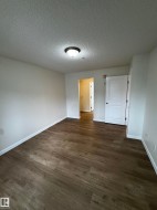 Spacious room featuring wood-finish flooring, white baseboards, and a neutral wall palette - 