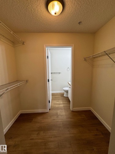 Walk-in closet featuring wood-finish flooring, wire shelving, and a flush mount ceiling light - 136 16221 95 Street, Edmonton, AB - Indoor With Storage