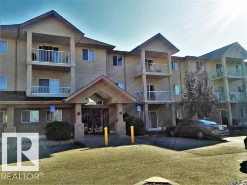 The property features a multi-story building with a stucco exterior and pitched roofs - 136 16221 95 Street, Edmonton, AB - Outdoor With Balcony With Facade