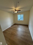 Bedroom featuring wood-finish flooring, a ceiling fan with integrated lighting, and a window with white trim - 