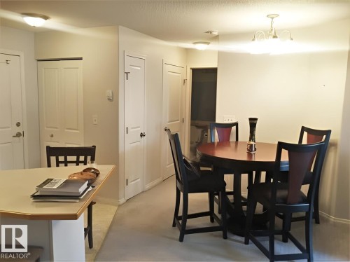 This area features light-colored walls and carpeted flooring, with a dining space illuminated by a ceiling light fixture - 136 16221 95 Street, Edmonton, AB - Indoor Photo Showing Dining Room