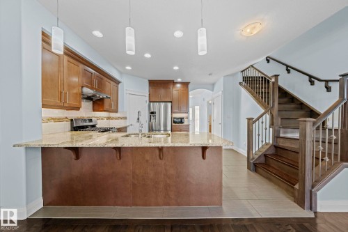 The property features a kitchen with wood cabinetry, stainless steel appliances, and a granite countertop island with integrated sink - 12913 124 Street, Edmonton, AB - Indoor Photo Showing Kitchen With Upgraded Kitchen
