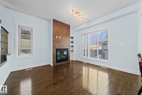This interior features dark hardwood floors and light-colored walls - 12913 124 Street, Edmonton, AB - Indoor Photo Showing Living Room With Fireplace