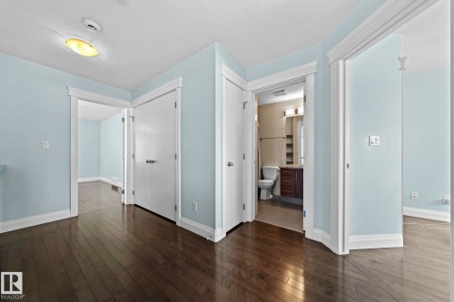 The property features dark hardwood flooring throughout, light blue walls, and white trim - 12913 124 Street, Edmonton, AB - Indoor Photo Showing Other Room