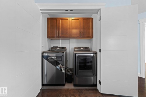 The property includes a dedicated laundry area with a washer, dryer, and overhead wooden cabinetry, all set on a dark wood floor - 12913 124 Street, Edmonton, AB - Indoor Photo Showing Laundry Room