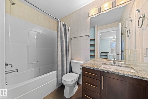Bathroom featuring a combination shower and bathtub, a dark wood vanity with a granite countertop, and a vanity mirror with overhead lighting - 12913 124 Street, Edmonton, AB - Indoor Photo Showing Bathroom