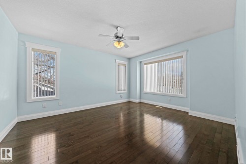 The room features dark hardwood flooring, light blue walls, and a ceiling fan with integrated lighting - 12913 124 Street, Edmonton, AB - Indoor Photo Showing Other Room