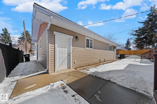 The property features light-colored horizontal siding, a white door, and white-framed windows, all under a pitched roof with white eaves - 12913 124 Street, Edmonton, AB - Outdoor With Exterior