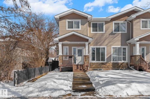The property features a multi-level facade with light-colored siding, a stone accent base, and white trim around the windows - 12913 124 Street, Edmonton, AB - Outdoor With Facade