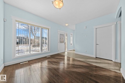 This bright room features wide plank hardwood flooring and a large window with vertical blinds, allowing ample natural light - 12913 124 Street, Edmonton, AB - Indoor Photo Showing Other Room