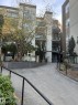 The property features a concrete pathway leading to the building entrance, bordered by a black metal railing and landscaping with various plantings and trees - 443 10403 122 Street, Edmonton, AB  - Outdoor 