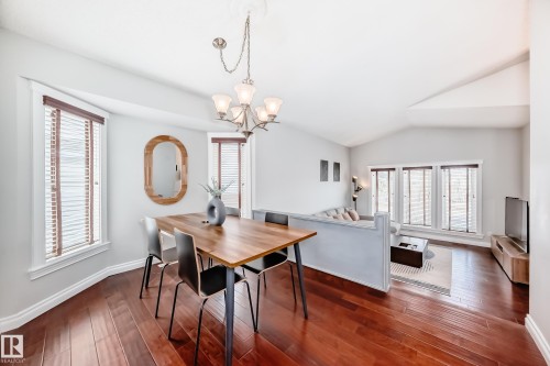 The dining area features rich hardwood flooring and a chandelier, with natural light entering through multiple windows with blinds - 3107 43 Avenue, Edmonton, AB - Indoor Photo Showing Dining Room