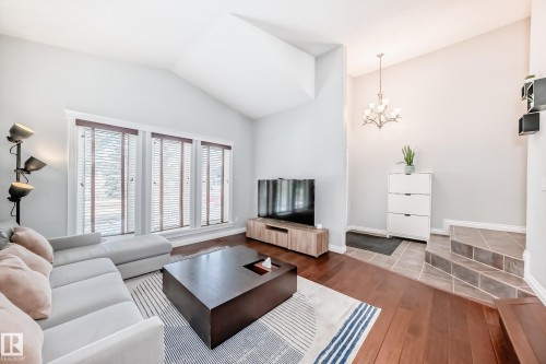 The living area features vaulted ceilings, rich hardwood flooring, and large windows with blinds - 3107 43 Avenue, Edmonton, AB - Indoor Photo Showing Living Room