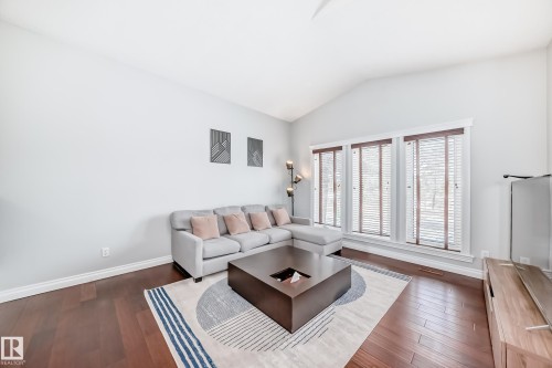 Living area featuring rich hardwood floors, an angled vaulted ceiling, and three large windows with wooden blinds - 3107 43 Avenue, Edmonton, AB - Indoor Photo Showing Living Room