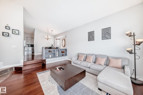 The living area features hardwood flooring, a built-in shelving unit, and recessed lighting - 3107 43 Avenue, Edmonton, AB - Indoor Photo Showing Living Room