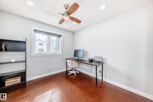 This room features rich brown flooring, a window providing natural light, and a ceiling fan with integrated lighting - 3107 43 Avenue, Edmonton, AB - Indoor Photo Showing Office