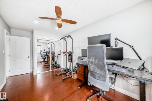 This room features rich brown flooring, a ceiling fan with wooden blades, and white walls - 3107 43 Avenue, Edmonton, AB - Indoor