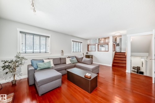 The living area features polished hardwood floors, two windows with blinds, and white walls - 3107 43 Avenue, Edmonton, AB - Indoor Photo Showing Living Room
