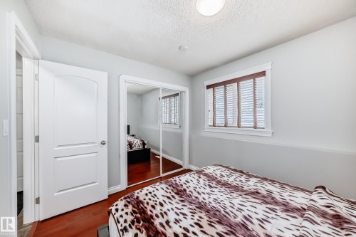 This room features light gray walls, a window with white blinds and dark wood trim, and a mirrored closet - 3107 43 Avenue, Edmonton, AB - Indoor Photo Showing Bedroom