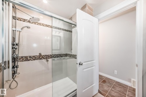The bathroom features a spacious shower with a glass enclosure, tiled walls with decorative mosaic accents, and a rainfall showerhead alongside a handheld shower fixture - 3107 43 Avenue, Edmonton, AB - Indoor
