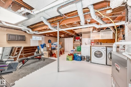 The property features an unfinished space with exposed ceiling joists, a window, and a utility area with a sink and appliances - 3107 43 Avenue, Edmonton, AB - Indoor